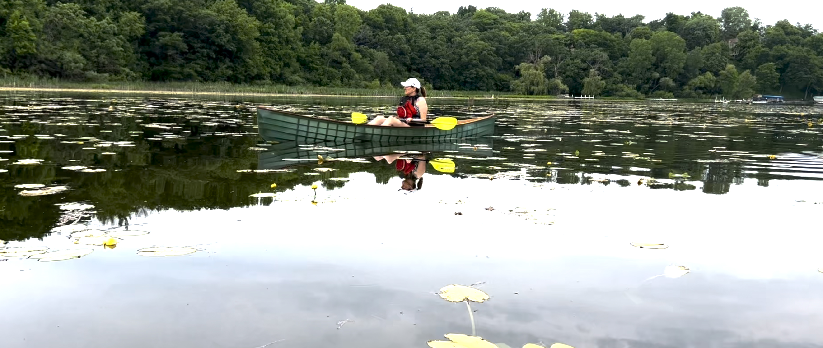 Image of a boat builder paddling a skin-on-frame canoe.