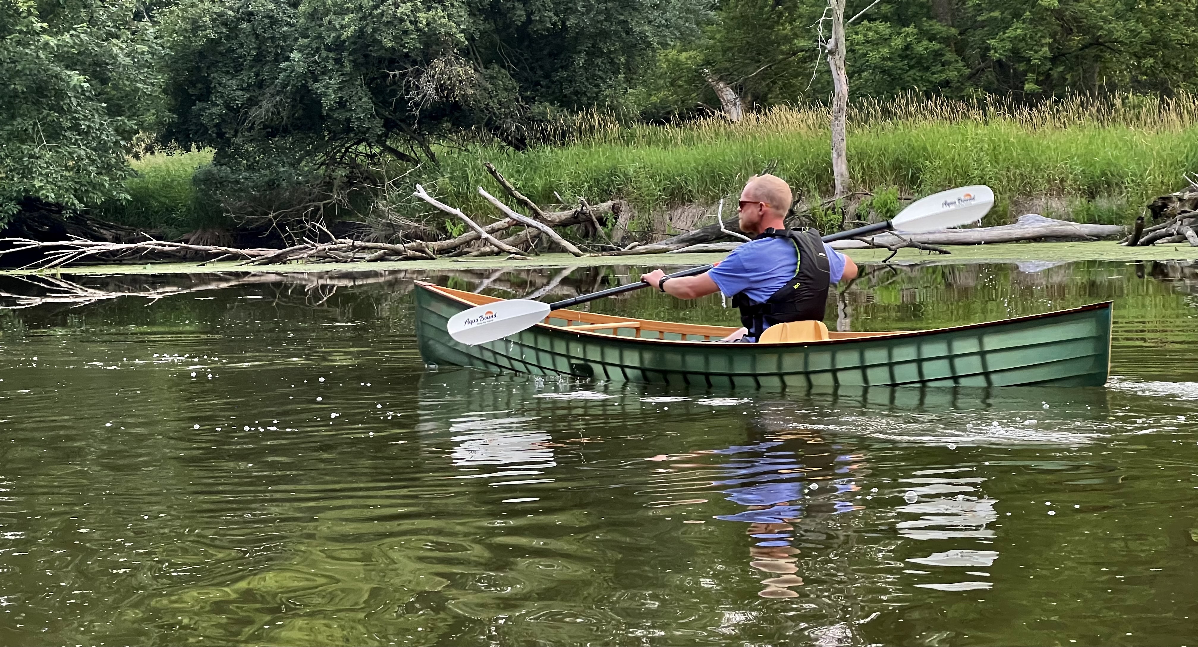 Image of man in green canoe paddling on Skokie Lagoons.